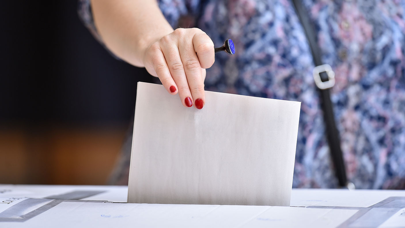 Woman inserts a voting paper into a ballot box