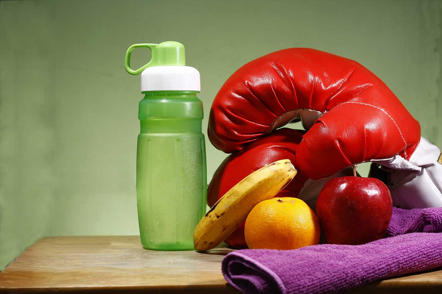 Close-up of fruits with boxing gloves and water bottle.